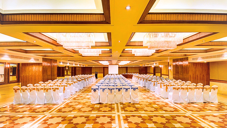 A spacious banquet hall at Pride Plaza Ahmedabad, featuring a large number of tables arranged in rows, ready for a conference or event.